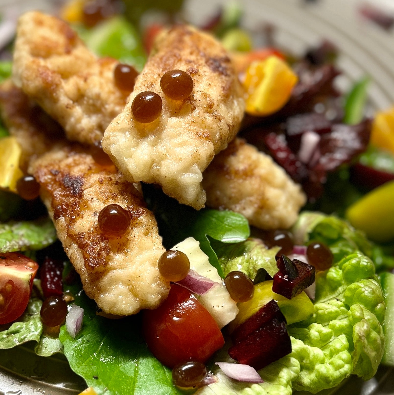 Flathead, Salad and Sticky Balsamic Pearls with tomato, red onion, beetroot, lettuce on a grey plate