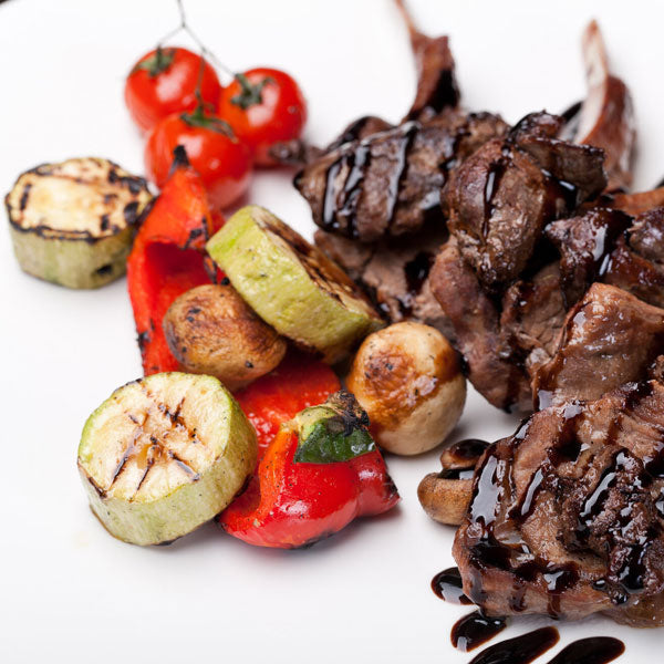 Lamb chops with grilled vegetables and Sticky Balsamic on a white background