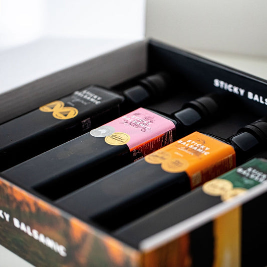 Sticky Balsamic Gift Box showing an open close up photo of the gift box with four bottles in it. The focus is in the middle of the gift box showing photographic artistry with a white background.