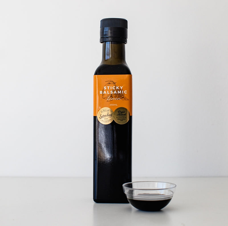 Sticky Balsamic Lemon 250ml bottle with a clear bowl of balsamic next to it. The background is white
