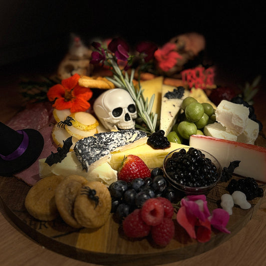 Halloween platter with cheese, biscuits and Sticky Balsamic pearls and a skull on a wooden board