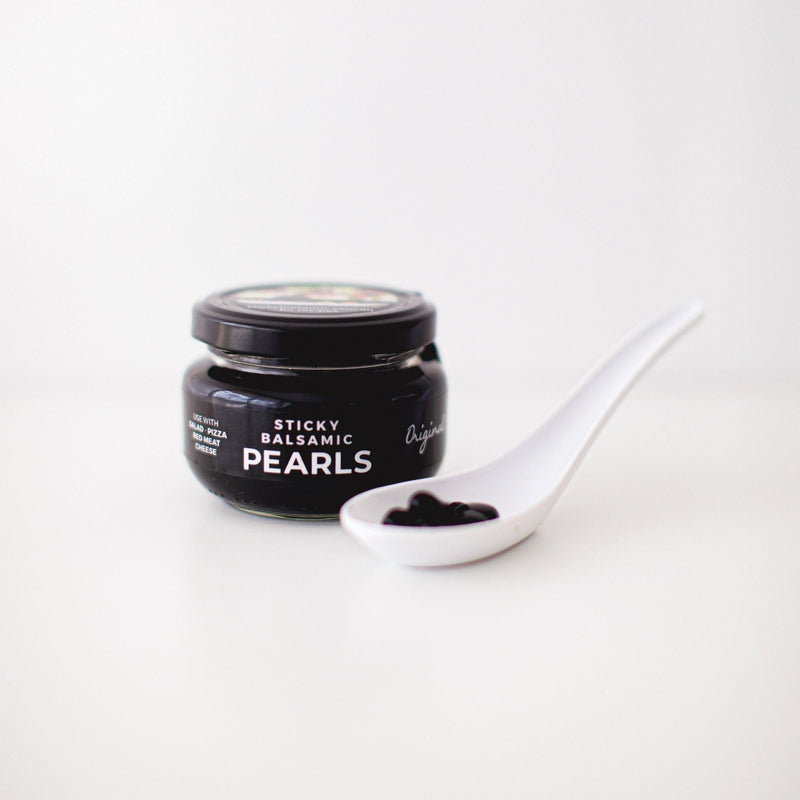 Sticky Balsamic Original Pearls in a jar with some in a spoon on a white background
