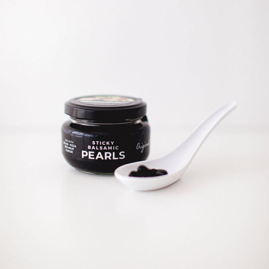 Sticky Balsamic Original Pearls in a jar with some in a spoon on a white background