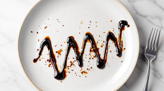 Sticky Balsamic Glaze on a white plate with a fork next to it, on a marble bench.