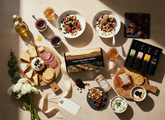 Luxury gourmet gift set featuring Sticky Balsamic Pearls, artisan cheeses, yogurt bowls with berries, honey, jams, nuts, chocolate, and premium condiments arranged beautifully for gifting.