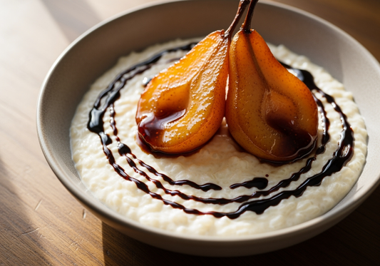 Creamy rice pudding topped with halved balsamic poached pears glistening with Sticky Balsamic Premium Fig glaze, elegantly arranged in a grey ceramic bowl