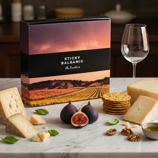 Sticky Balsamic Gift Box with gourmet cheese, artisan crackers, fresh figs, walnuts, and wine glass on marble surface, luxury gift presentation