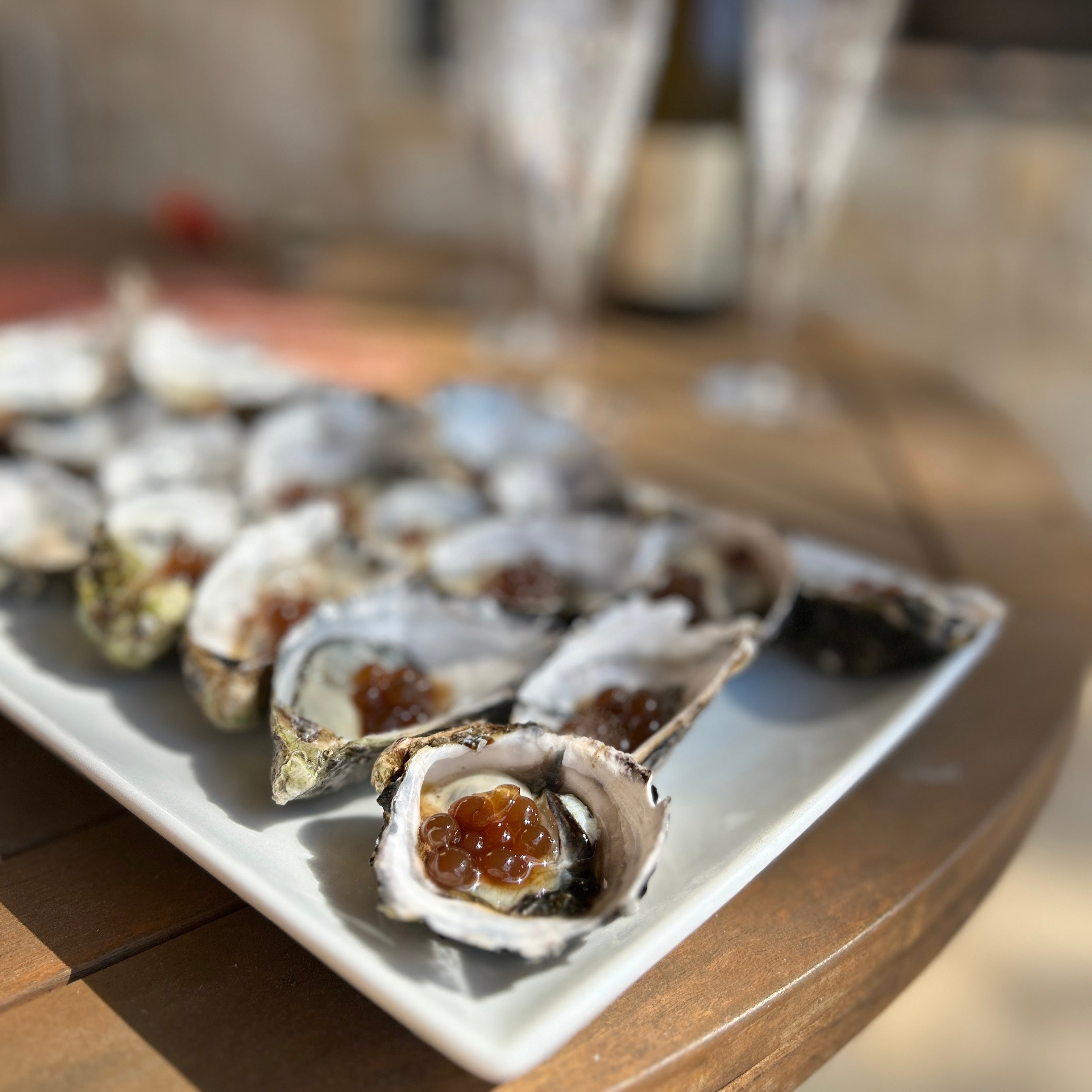 Oysters with sticky balsamic pomegranate pearls on a white square plate