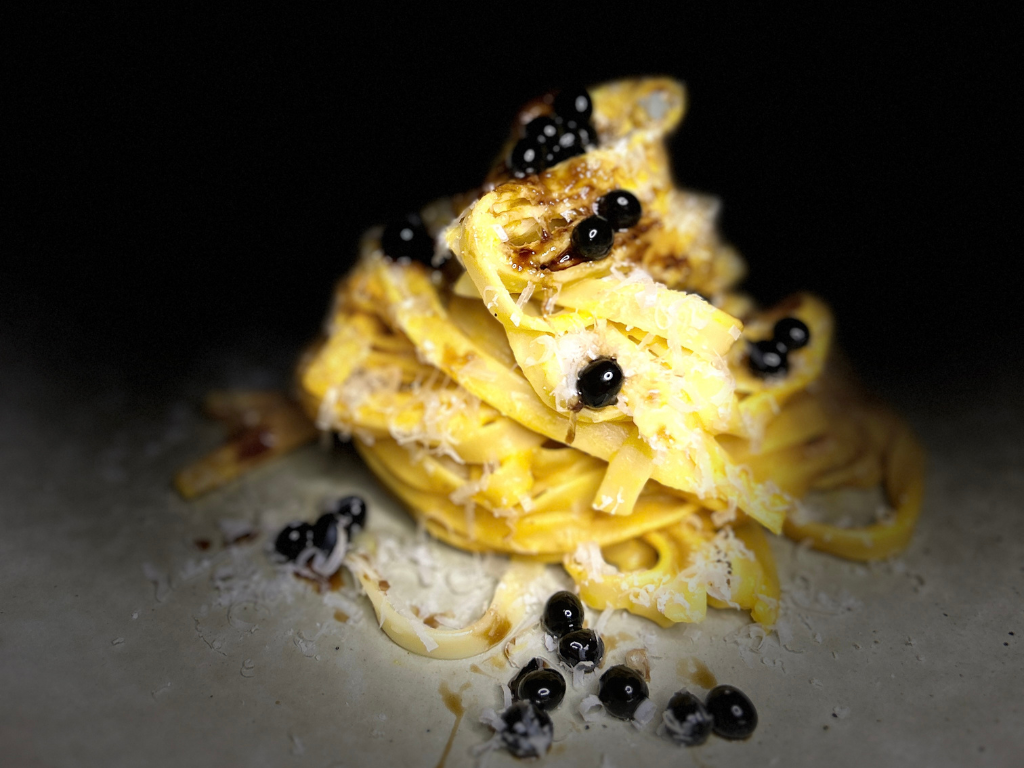 Pumpkin Pasta with Sticky Balsamic Pearls and shaved parmesan stacked high, on a grey plate and dark background