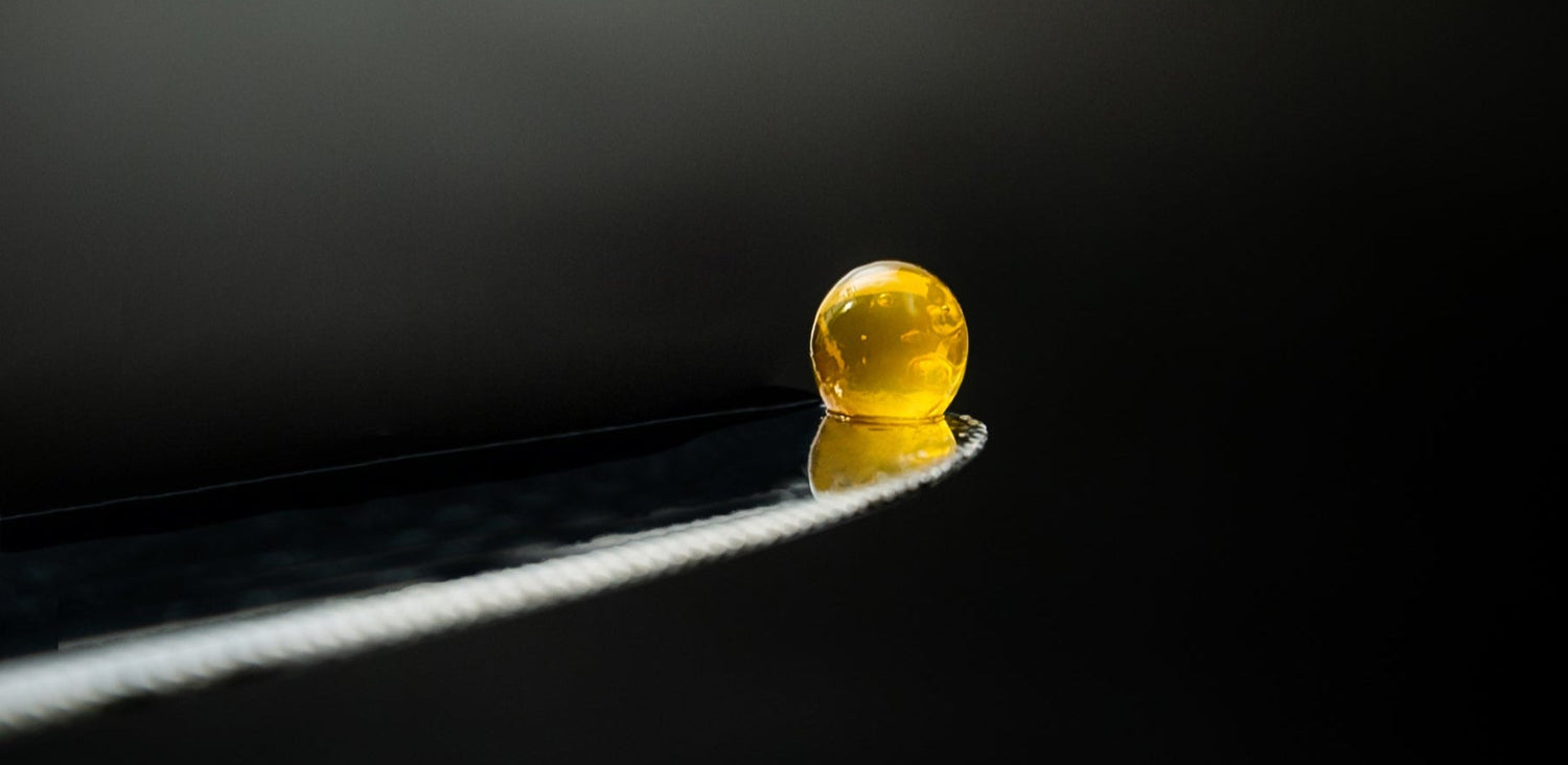 Single Sticky Balsamic Premium Quince Pearl on a silver knife, close up showing artistic impression