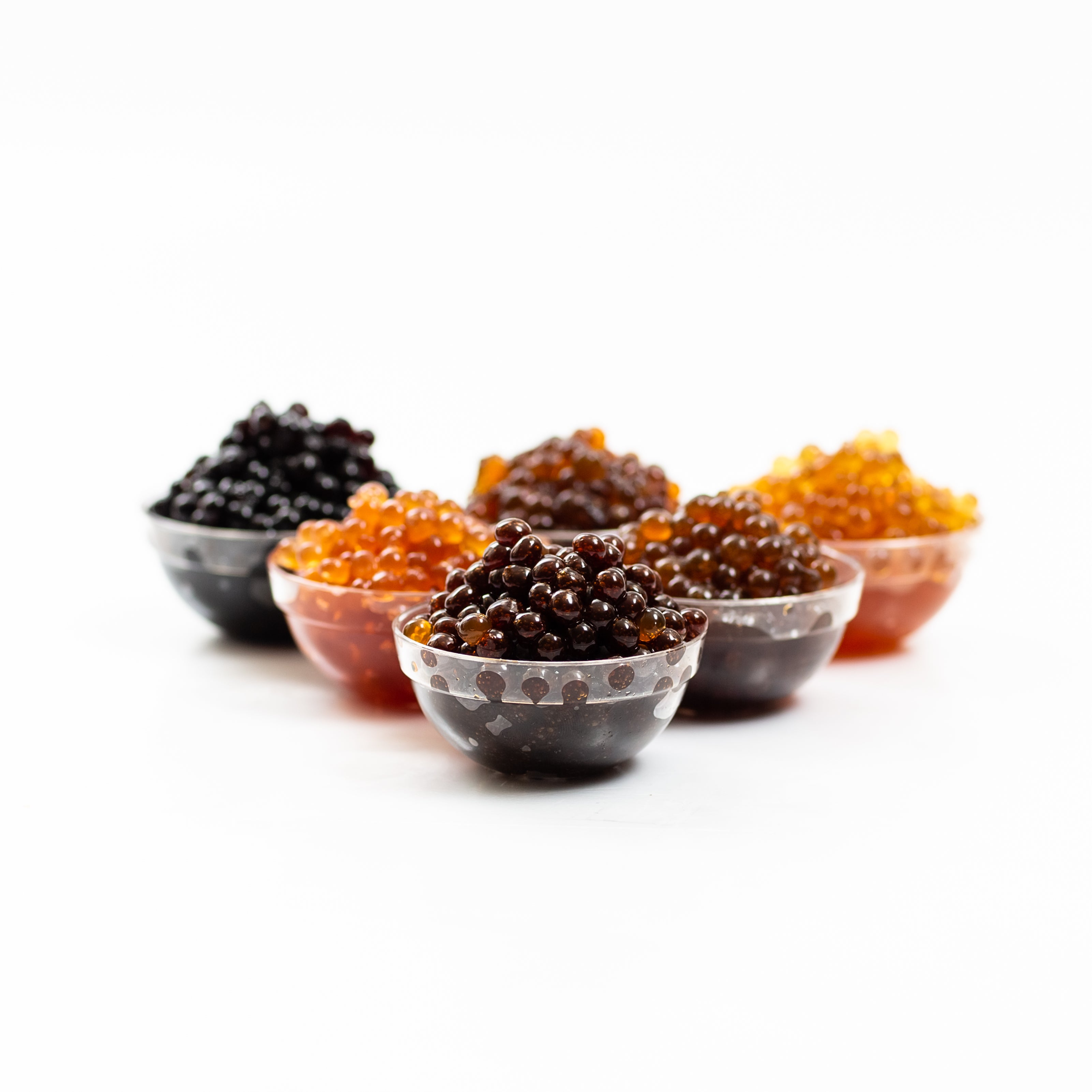 Sticky Balsamic Pearls in plastic cups showing the individual pearls with a white background