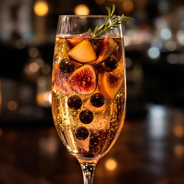 Elegant Fig Pearl Sunset Fizz cocktail in champagne flute topped with Sticky Balsamic Premium Fig Pearls and fresh thyme garnish