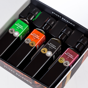 Premium balsamic vinegar bottles arranged in elegant gift box packaging, featuring multiple award-winning varieties perfect for gourmet cooking.
Sticky Balsamic Luxurious bottle gift box on a white background showing four different bottles of Sticky Balsamic packaged and looking beautiful