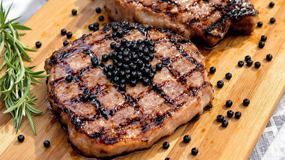 Seared steaks topped with balsamic pearls on a wooden cutting board
