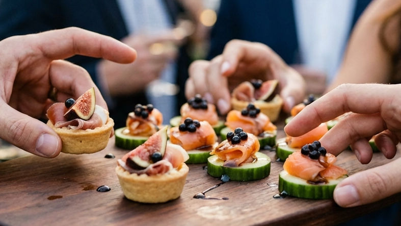 People enjoying small appetizers on a wooden tray at an outdoor event.