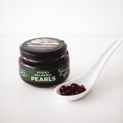 Sticky balsamic truffle pearls jar with small spoon holding dark pearls
